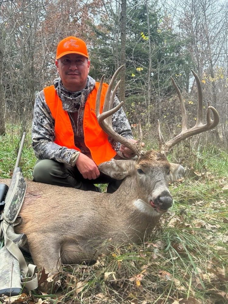 Rifle hunter in blaze orange with a heavy-beamed Missouri whitetail buck