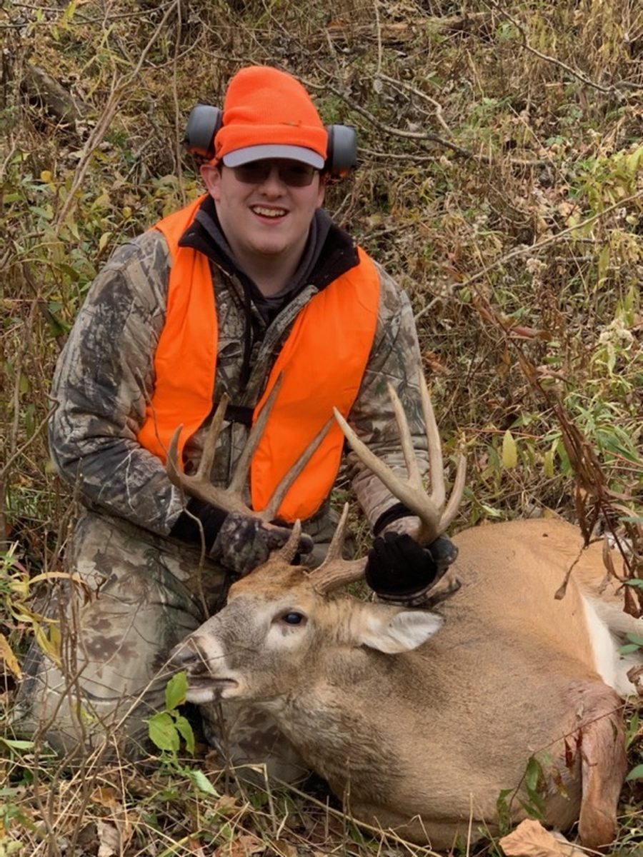 Hunter kneeling with a heavy-beamed Missouri whitetail buck at dusk
