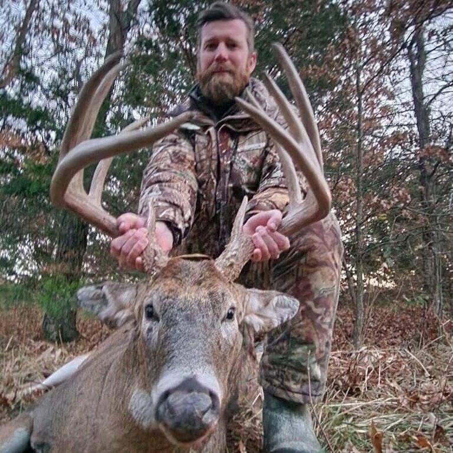 Hunter kneeling behind a wide, long-tined Missouri whitetail buck